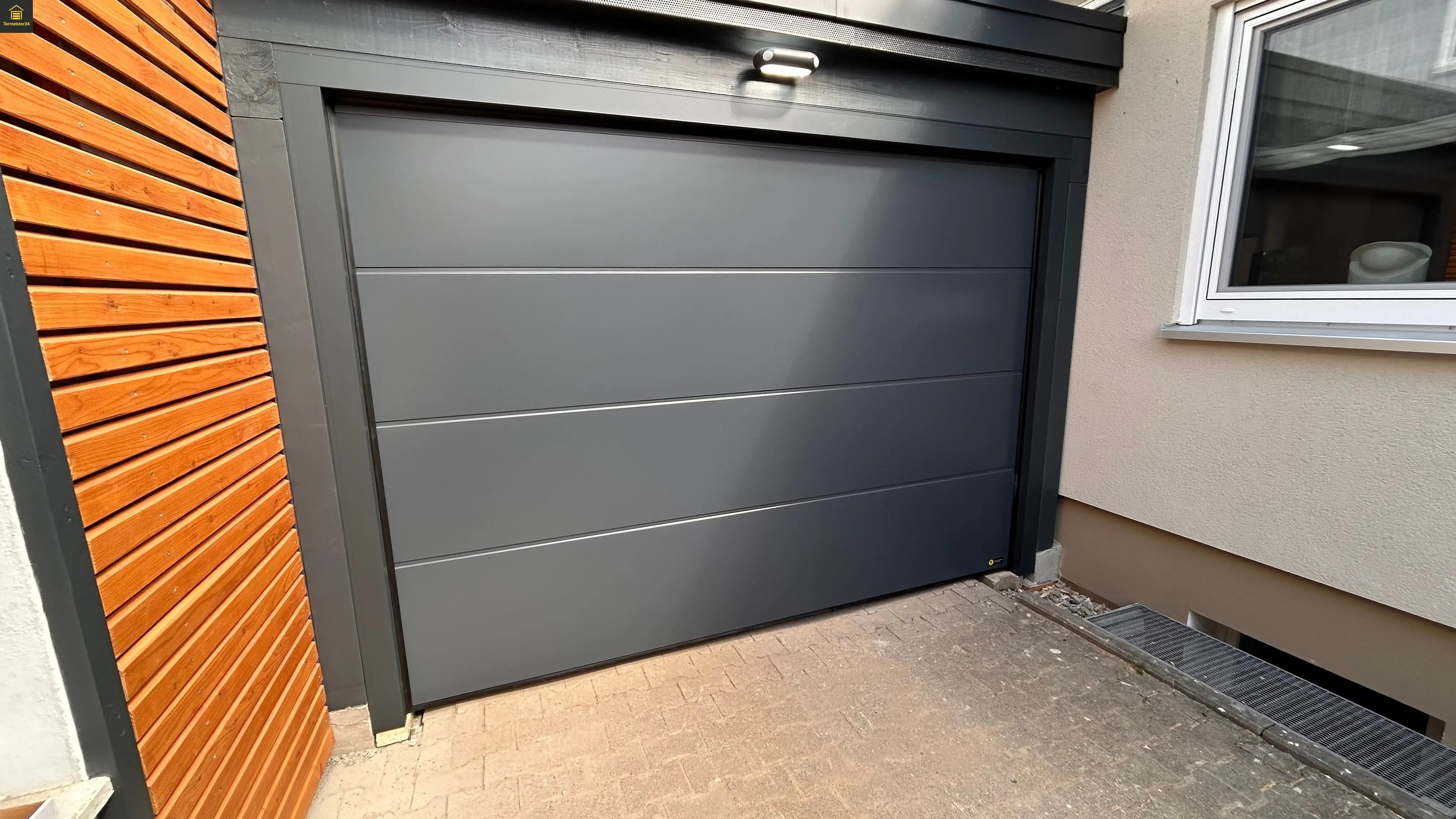 Modernes Garagen-Sektionaltor als Komplettset mit Antrieb, Handsender, Wandschalter und Zubehör von Tormeister24 für komfortable und sichere Garagennutzung.